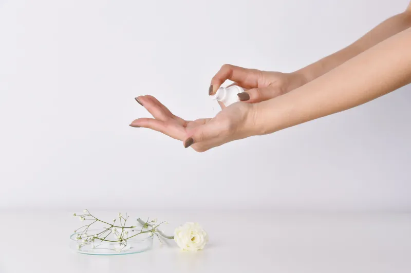 hands applying skincare moisturizer oil woman holding a cosmetic bottle containers, blank label for beauty product branding mock-up