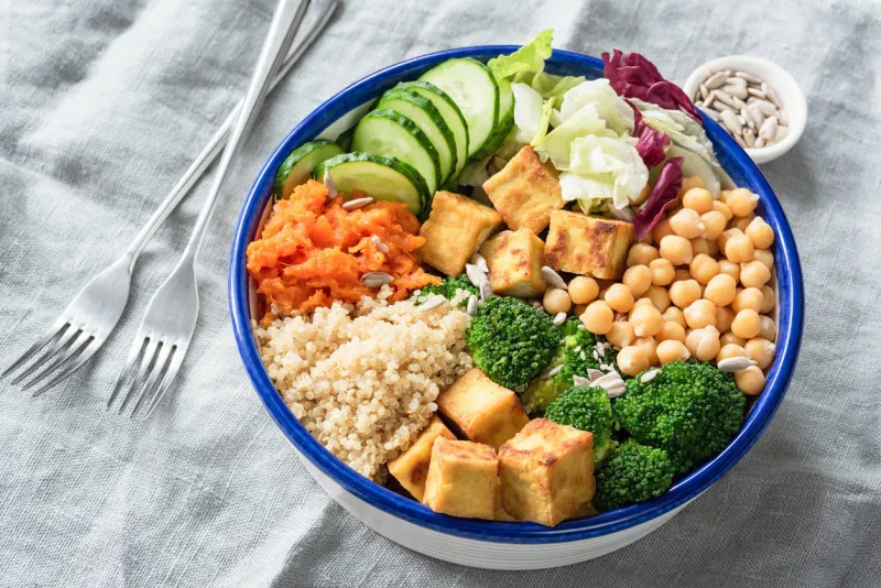 nourishing buddha bowl with tofu, quinoa and vegetables healthy eating, healthy lifestyle, vegan food, vegetarian diet, modern lifestyle concept colorful buddha bowl on table selective focus