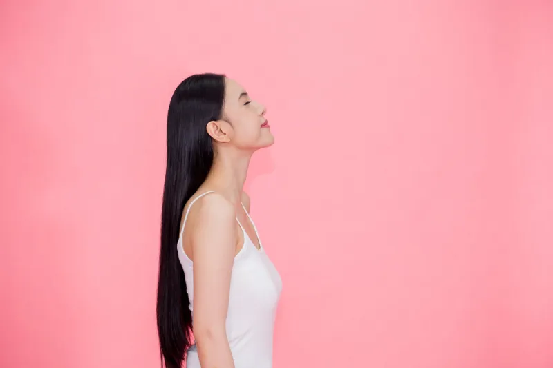 side view of young beautiful and calm asian woman isolated over pink background
