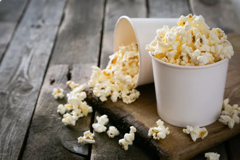 home made pop corn in white cups on wood background, copy space