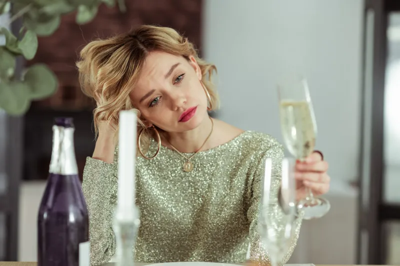 sad and lonely beautiful woman wearing nice jewelry feeling sad and lonely while drinking alcohol