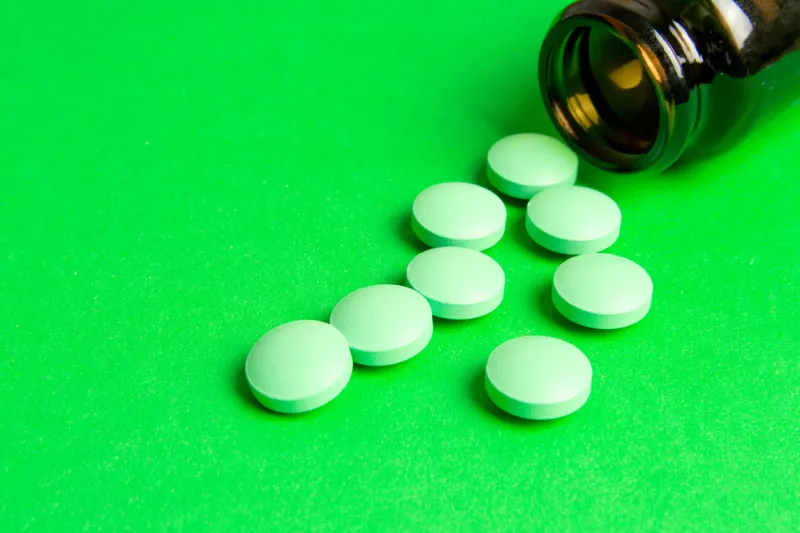 medicine green pills poured from a bottle on green background with copy space drug prescription for treatment medicine medical background, template