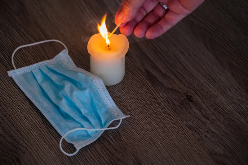 candles burning on wooden table background medical mask laying beside rest in peace people who died from a respiratory virus