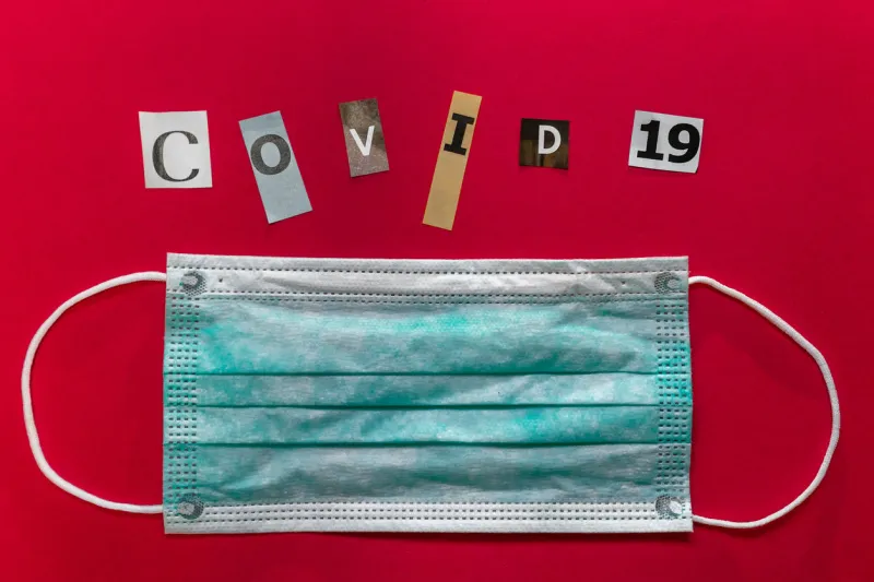 surgical face mask with covid-19 inscription on red backgroundthe letters of text are cut out of paper place for text chinese coronavirus outbreak novel coronavirus - 2019-ncov