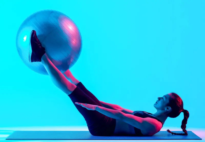 one mixed races woman exercsing fitness pilates exercices isolated on blue blackground