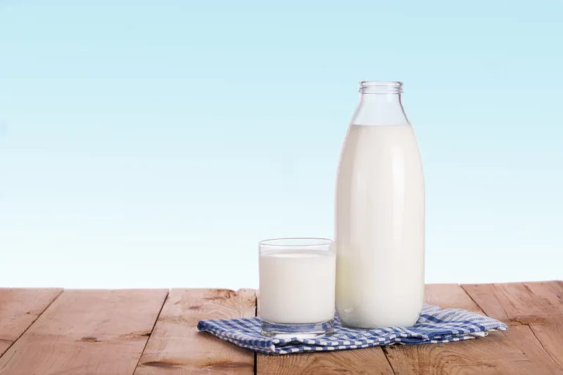 bottle of fresh milk and glass is wooden table