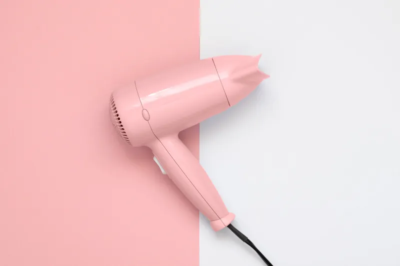 pink hair dryer on pink and white paper background