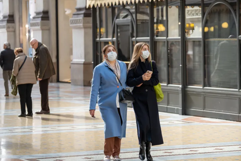 milan, italy - february 27, 2020  young women wearing white face mask walking through the galleria vittorio emanuele ii some people in italy began wearing face masks after italian authorities have announced coronavirus outbreak in the country