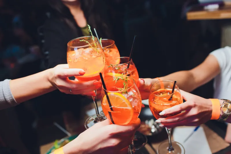 women raising a glasses of aperol spritz at the dinner table