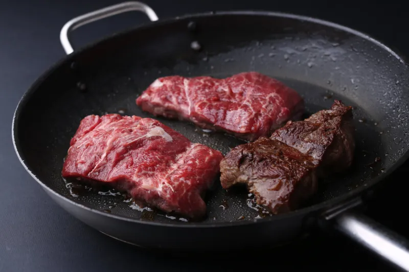 fresh tenderloin steaks in frying pan bkack backfround closeup