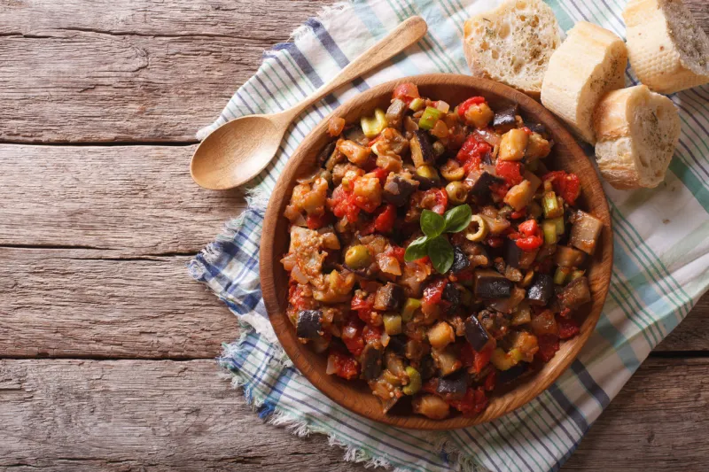 italian caponata with aubergines in a wooden plate horizontal view from above