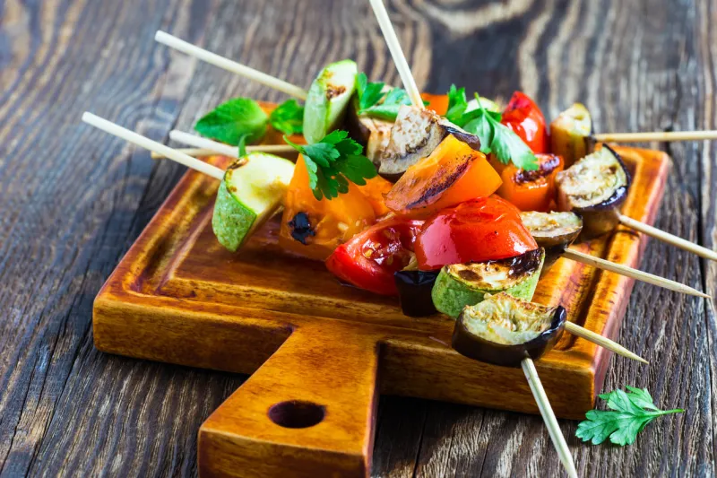 fresh summer vegetable kebabs with eggplant and cherry tomatoes, charred veggie skewers on cutting board, veggies eating concept