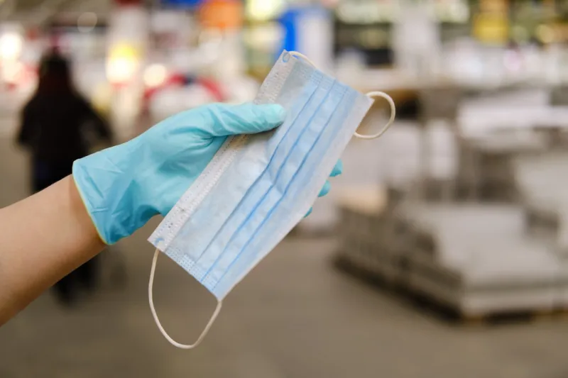 hand in a medical glove holds a mask on the background of the store, concept