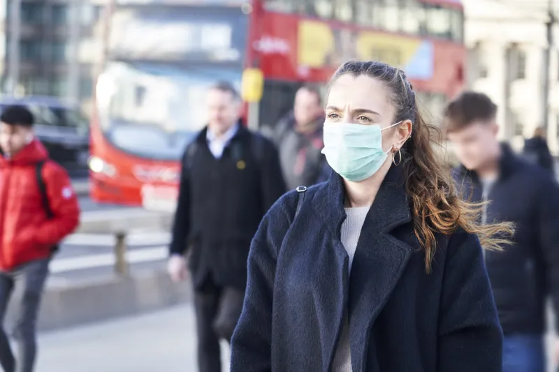 young woman wearing face mask while walking in the streets of london