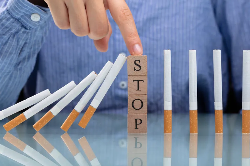 woman stopping cigarette from falling on desk with wooden blocks