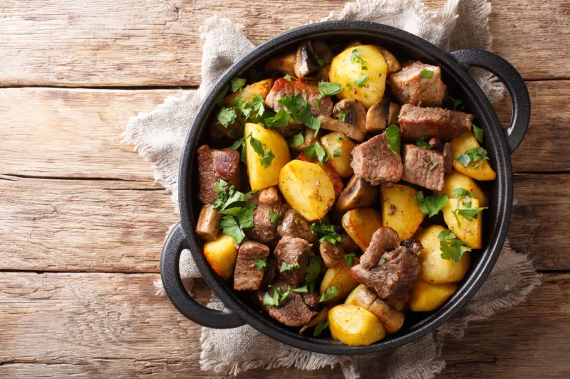 traditional fried potatoes with pork and mushrooms close-up in a pan on the table horizontal top view from above