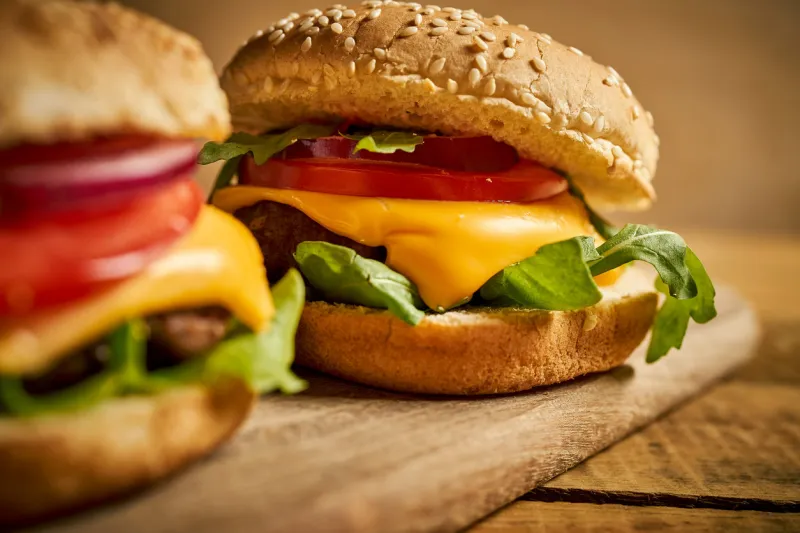 close up of tasty hamburger on wooden table and on black background