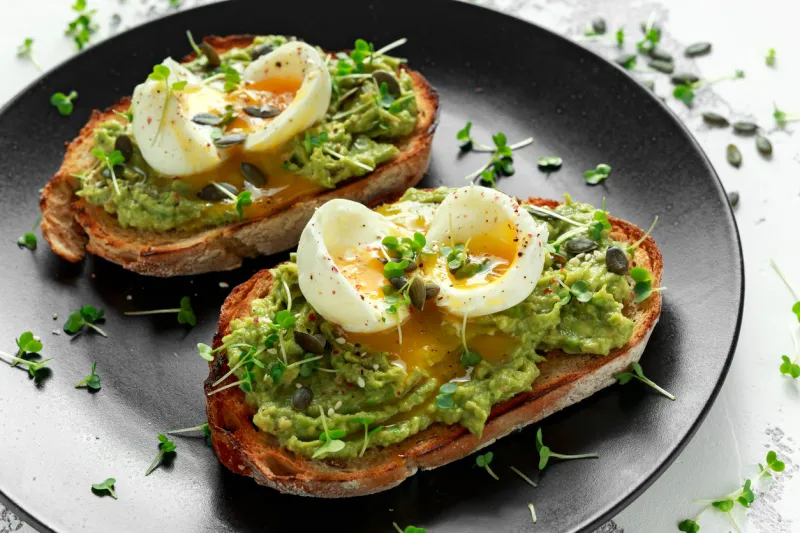 healthy avocado and egg toasts with pumpkin and sesame seeds, sprinkled with cress salad