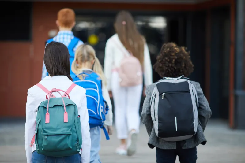 rear view of students with backpacks going to school for classes