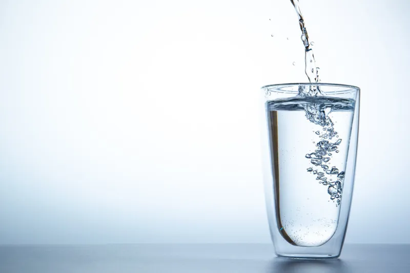 man filling water from the blue plastic bottle into double glass lighting set up shot on white background concept of good health and refreshment