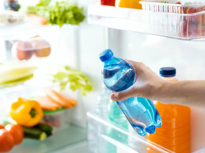 woman taking a bottle of fresh water from the fridge, beverage and hydration concept