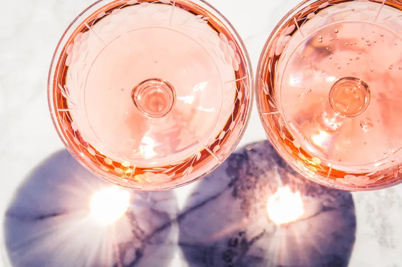 two crystal stemmed glasses with rose wine on marble table outdoors in a cafe aperitif and relax time