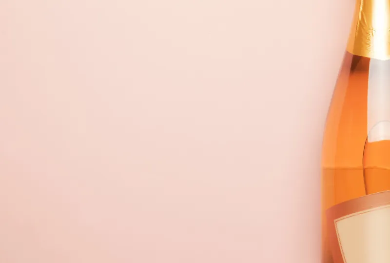 bottle with pink sparkling wine or rose champagne and glasses, trendy pink background with place for text, holiday or date concept, flat lay, top view