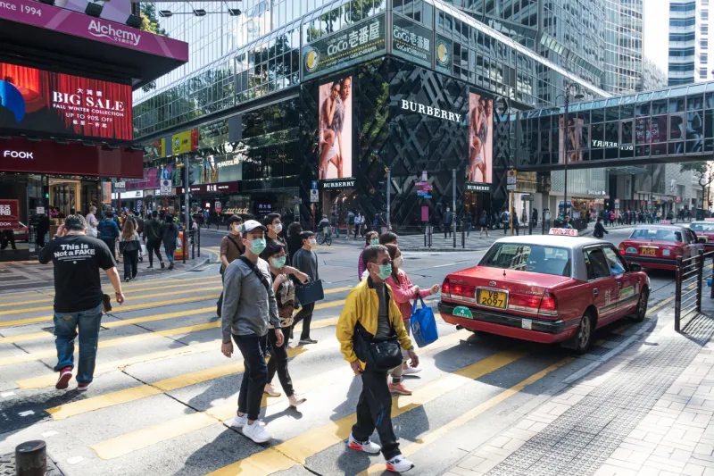 tsim sha tsui, hong kong - 22 february, 2020   people walking across nathan road kowloon, hong kong citizens fearing coronavirus wear masks on the street