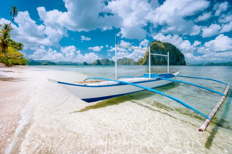 el nido, palawan, philippines tropical scenery of banca boat on the sandy beach ready for island hopping tour pinagbuyutan island in background