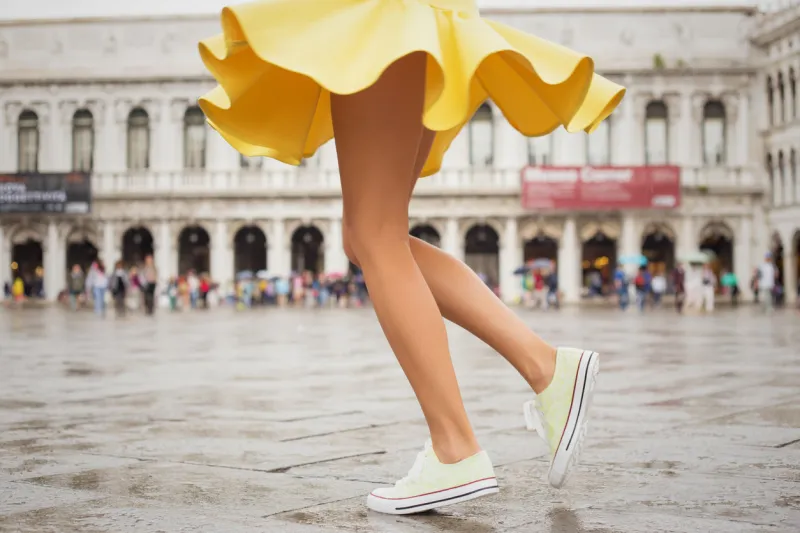 cheerful young woman with sexy legs and yellow skirt dancing