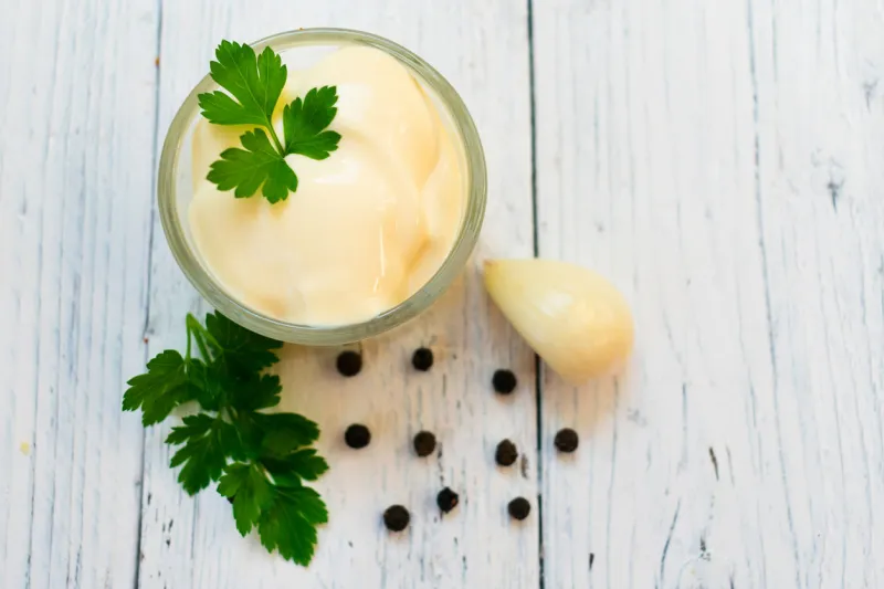 mayonnaise sauce and parsley, garlic on a white wooden background top view