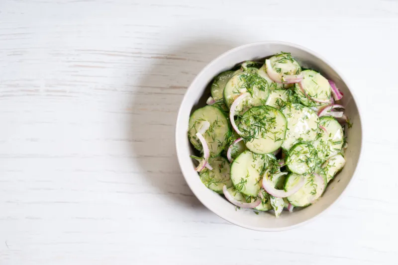 cucumber and red onion salad on white wooden background