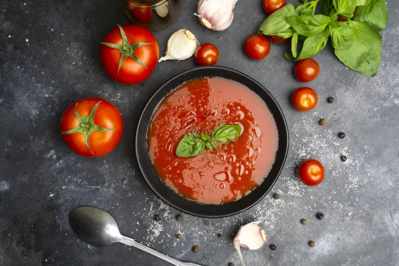 gazpacho cold summer vegetarian tomato soup with basil in a bowl on black stone background summer soup concept