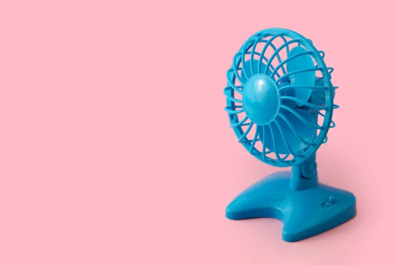 electric blue plastic fan isolated on pink background