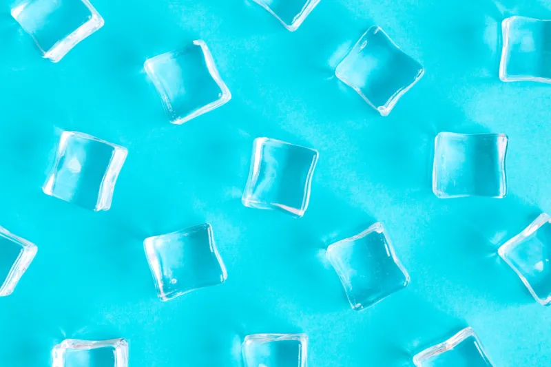 flat lay of ice cubes on bright blue background minimal drink and summer concept