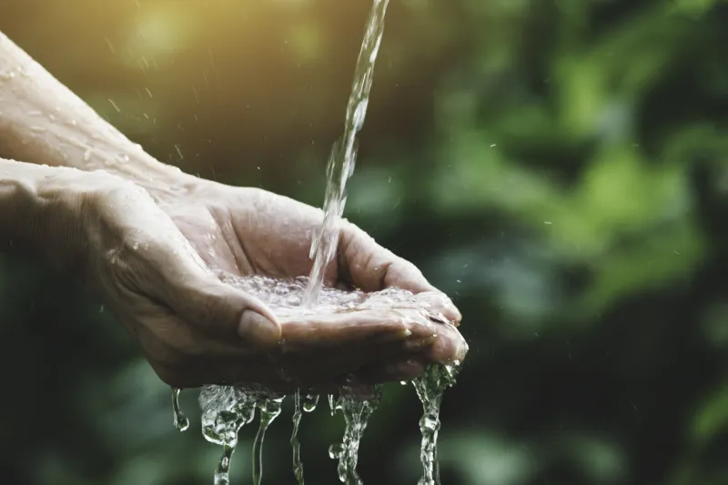 closeup water flow to hand of women for nature concept on the garden background