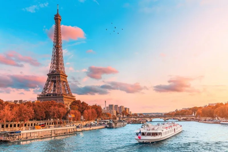 the main attraction of paris and all of europe is the eiffel tower in the rays of the setting sun on the bank of seine river with cruise tourist ships
