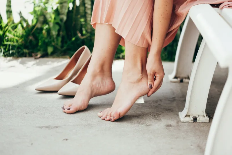 woman suffering from leg pain outdoors because of uncomfortable shoes