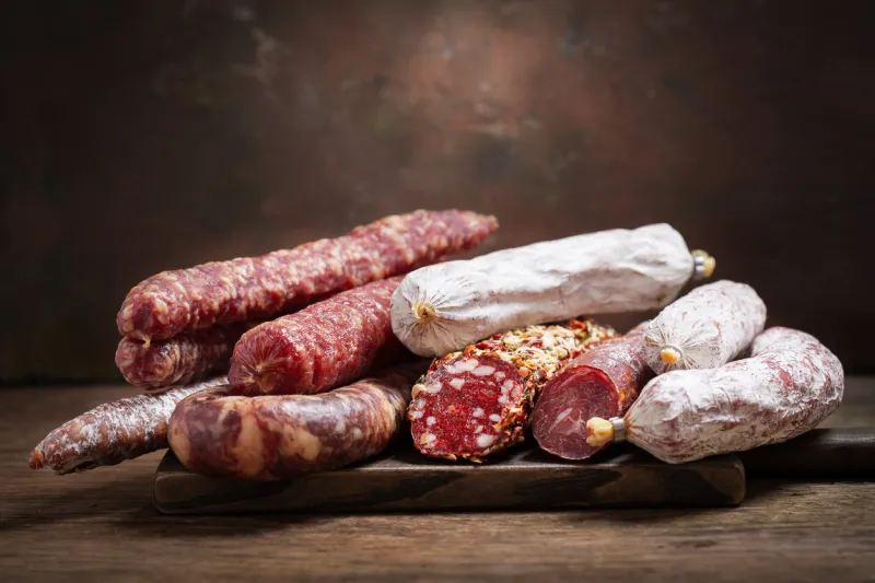 various kind types of salami and sausages on a wooden board
