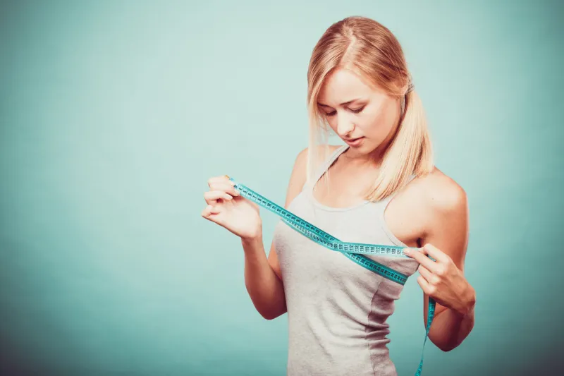 fitness woman fit girl in sportswear with measure tape measuring her size chest breast on blue