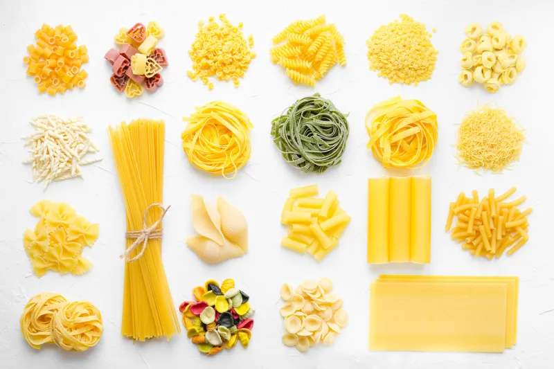 variety of types and shapes of italian pasta in rows on white background from above italian cuisine food concept and menu design dry pasta background texture top view flat lay