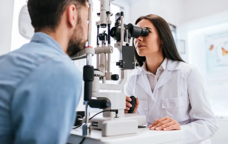 attractive female doctor ophthalmologist is checking the eye vision of handsome young man in modern clinic doctor and patient in ophthalmology clinic