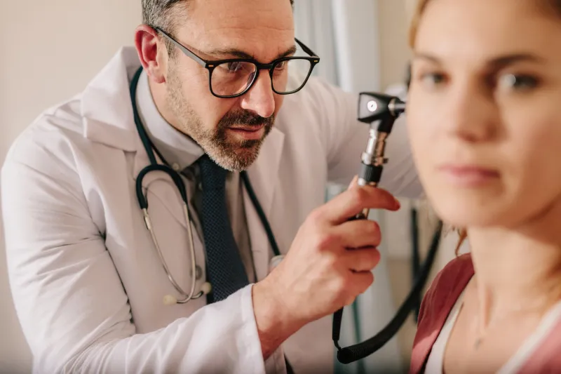 ent doctor checking ear with otoscope of woman patient at hospital physician examining ear of female patient with an instrument