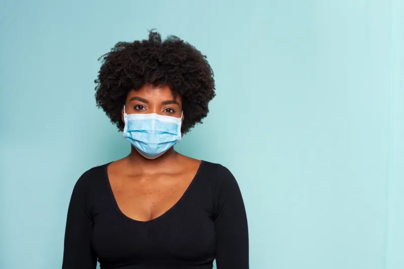 young woman wearing protection mask against covid-19 with blue background