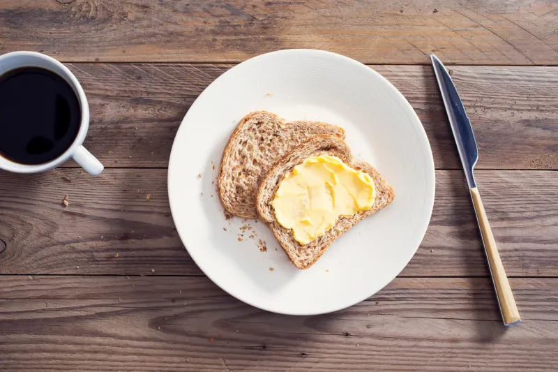 slices bread with butter on wooden table
