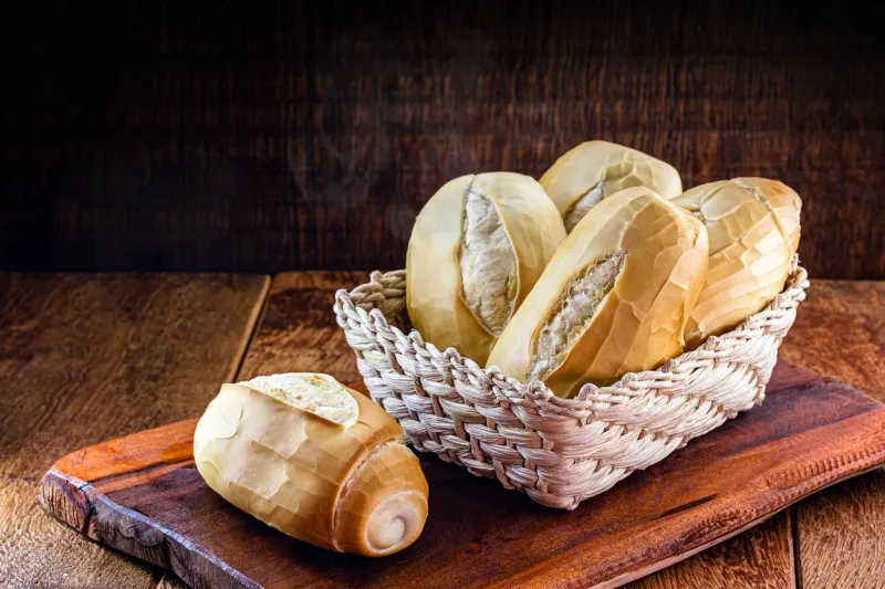 several traditional breads from brazil, on a rustic wooden background in a straw basket national day of brazilian french bread