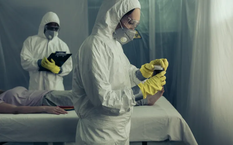doctors with bacteriological protection suits preparing medication for sick woman