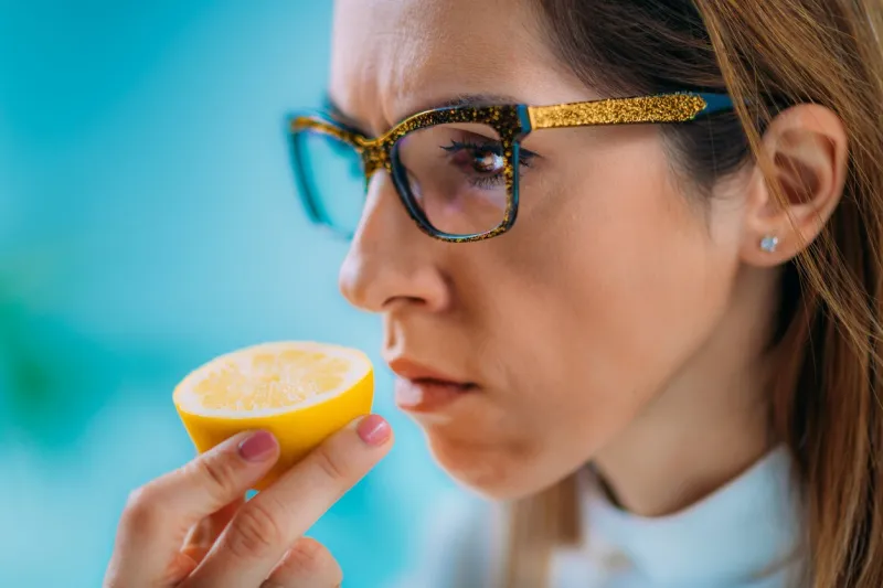 anosmia or smell blindness, loss of the ability to smell, one of the possible symptoms of covid-19, infectious disease caused by corona virus woman trying to sense smell of a lemon