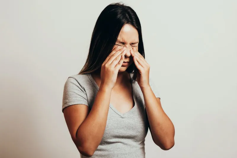 sinus pain, sinus pressure, sinusitis sad woman holding her nose and head because sinus pain