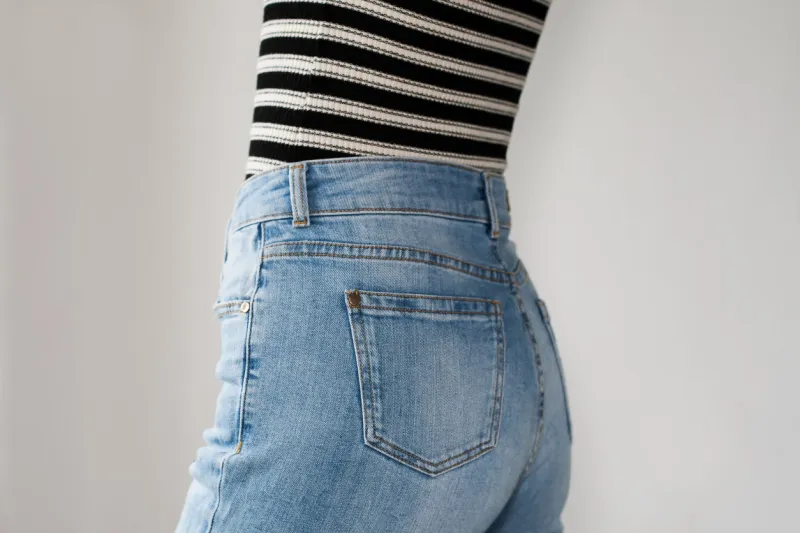girl dressed blue jeans and striped t-shirt, side view copy space white background